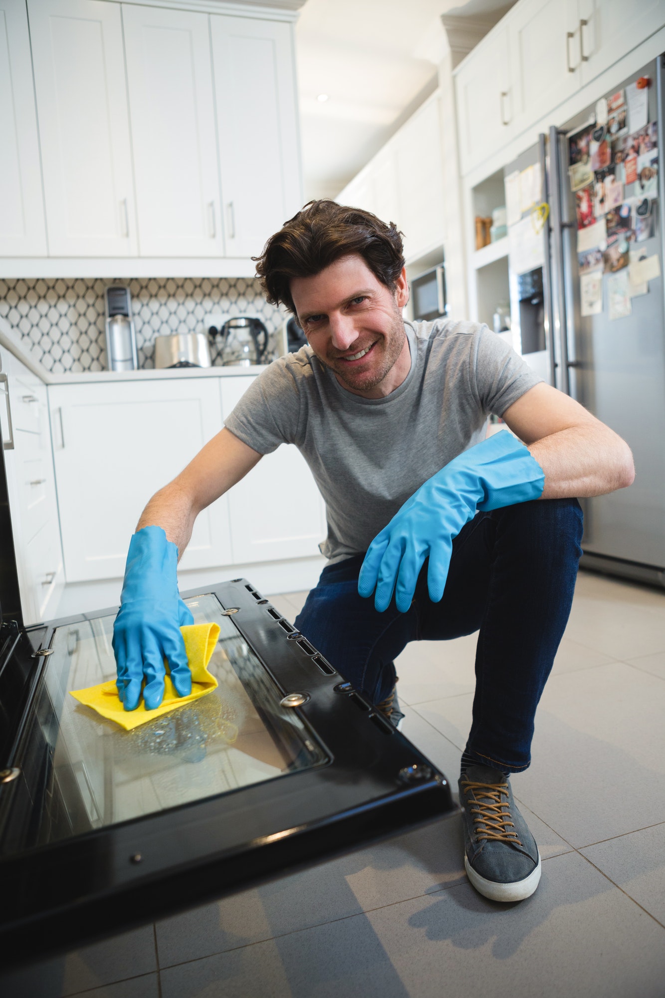Man cleaning gas oven in kitchen